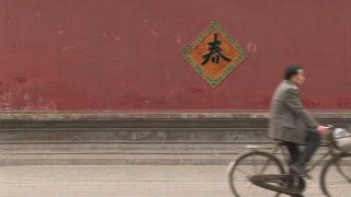 骑自行车经过一堵红墙视频素材模板下载
