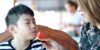 快乐的亚洲孩子与母亲喜欢吃熟西瓜。