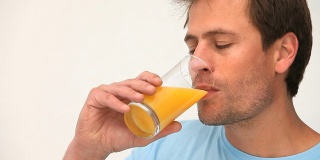 一个男人在喝一杯橙汁