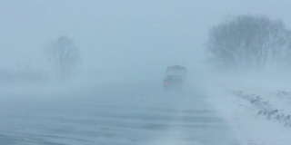 汽车在暴风雪的冬季道路上行驶