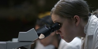 在生物实验室使用显微镜的学生