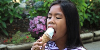 年轻的亚洲女孩吃冰淇淋蛋卷