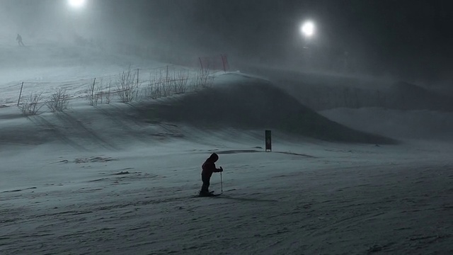 一个小男孩在暴风雪的夜晚去滑雪