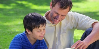 微笑的男子和他的儿子使用平板电脑
