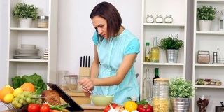 一个女人在厨房里用平板电脑做饭