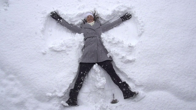 慢镜头:年轻女子在堆雪天使
