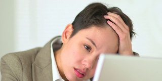 不开心的亚洲女商人在笔记本电脑上工作