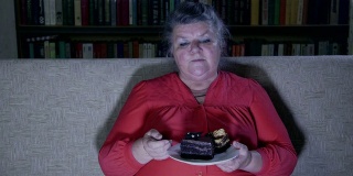 胖老女人一边看电视一边吃蛋糕