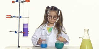 可爱的女孩马尾辫在统一和圆形眼镜混合两种液体，站在桌子旁边的白色背景化学实验