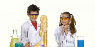 两个可爱的化学家孩子做有趣和成功的实验孤立在白色背景，慢动作