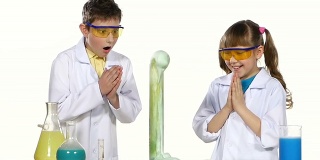 两个可爱的化学家孩子做有趣和成功的实验与蓝色泡沫孤立在白色背景，慢动作