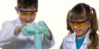 两个可爱的化学家孩子做有趣和成功的实验与蓝色泡沫，玩，得到快乐孤立在白色背景，慢镜头，近距离