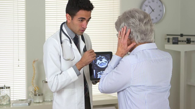 墨西哥医生向一位老年妇女解释脑部扫描