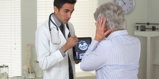 墨西哥医生向一位老年妇女解释脑部扫描
