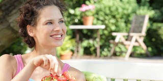 坐在长凳上吃草莓的女人。