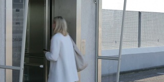 金发女人在等电梯时用手机发短信