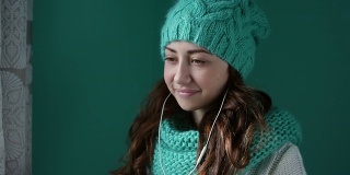 漂亮的女孩戴着针织帽听着耳机听音乐