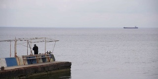 码头上一个渔夫和船靠海