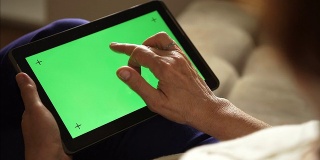 一位老年妇女正在使用绿色屏幕的平板电脑