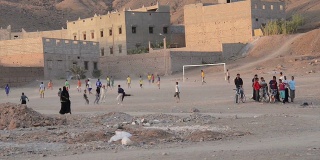 晚上，男孩和男人在泰姆格鲁特的沙滩上踢足球