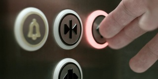 一名男子按下按钮打开电梯门。近距离