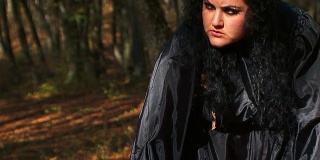 黑头发的女人在秋天的森林里凝视着远方