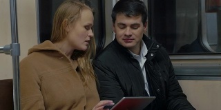 年轻人在移动的地铁列车上使用平板电脑