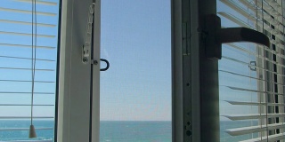 透过打开的白色窗户可以看到海景