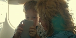 孩子和奶奶在飞机上玩手机