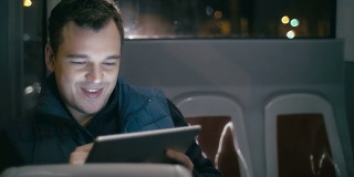 在公车上微笑着拿着平板电脑的男人