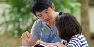 亚洲小女孩和爸爸在桌子上做作业
