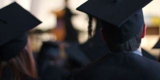 在大学毕业典礼上，兴奋的学生们戴着学士帽和学士服鼓掌