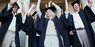 快乐的毕业生举起了他们的手臂