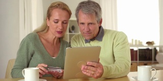 一对老年夫妇在桌上使用平板电脑