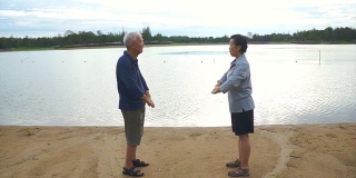 亚洲老夫妇在湖边练习太极、气功的视频