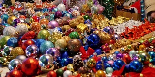 一个圣诞市场的画面，很多圣诞树的装饰品暴露在桌子上待售