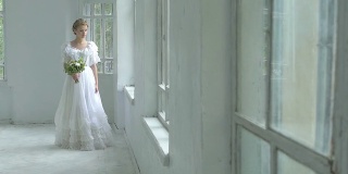 美丽的女孩穿着白色的衣服走过带花的窗口，慢镜头