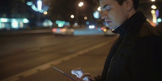 一名男子在等公交车时用平板电脑写信