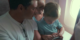 男孩玩智能手机游戏，他的父母