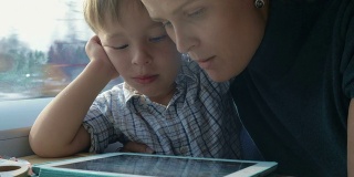 男孩和他的妈妈在平板电脑上看动画片