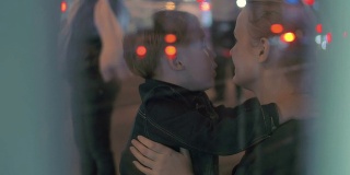 疲惫的男孩在公共汽车站拥抱妈妈