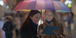 女性朋友在城市的雨天晚上使用触控板
