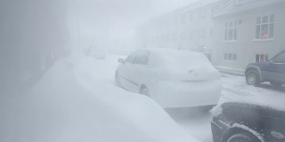 冰岛雷克雅未克，白雪覆盖的雪堆阻塞了居民区的人行道上的汽车