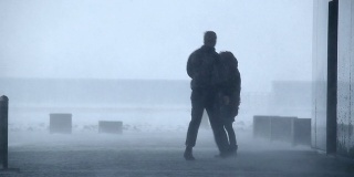 在冰岛雷克雅未克的暴风雪中，一名男子和一名女子站在建筑外