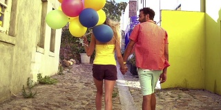 一对带着气球在小巷里散步的情侣