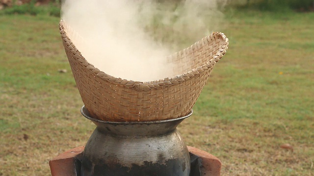 把米饭粘在竹编和锅里蒸熟。