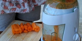 现代电动搅拌机用胡萝卜榨汁。生的胡萝卜汁