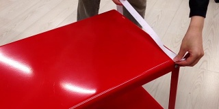 一个女人在宜家店里测量红色桌子的尺寸