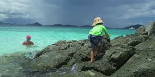 video of child climbing the rocks on a beach shoreline