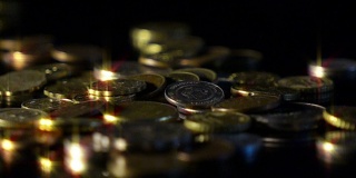 各国钱币的币值落在黑色反光面上，动作缓慢。金钱、生意、收入概念。